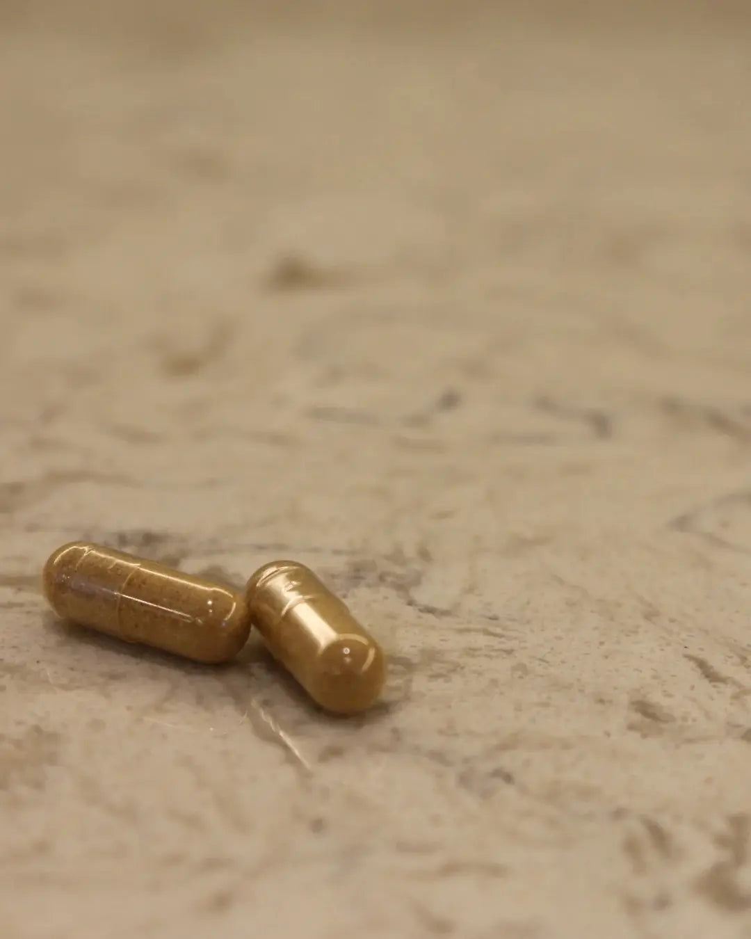 Deux gélules végétales de compléments alimentaires Atout Santé Nature posées sur un fond texturé, représentant notre exigence de qualité et notre ambition à échelle humaine Image