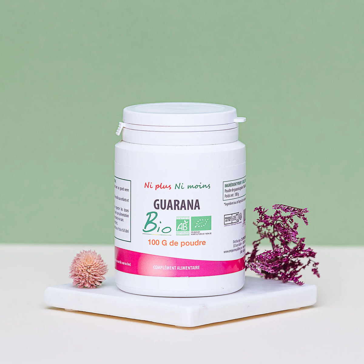 Flacon de poudre de Guarana Bio 100g Atout Santé Nature, complément alimentaire naturel présenté sur un socle blanc avec des fleurs séchées.